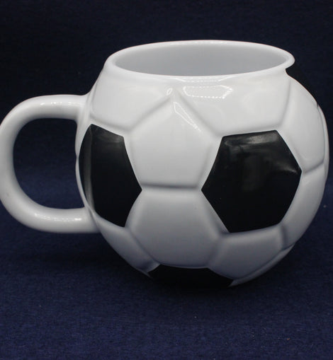 White ceramic mug shaped like a soccer ball on a dark background