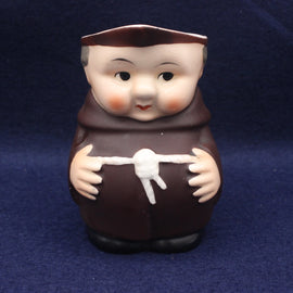 Stylized figurine of a monk holding a white object on a dark blue background