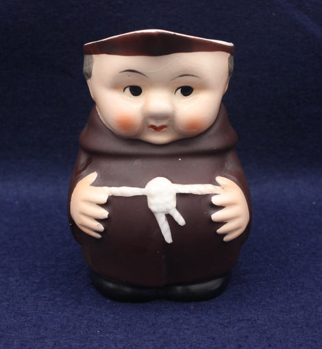 Stylized figurine of a monk holding a white object on a dark blue background