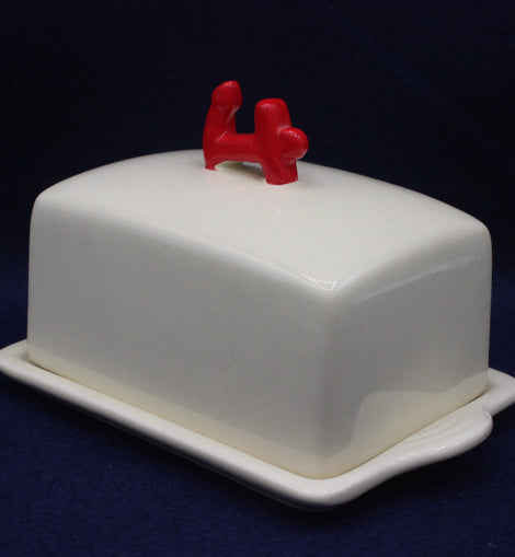 White butter dish with a red anchor on a dark blue background