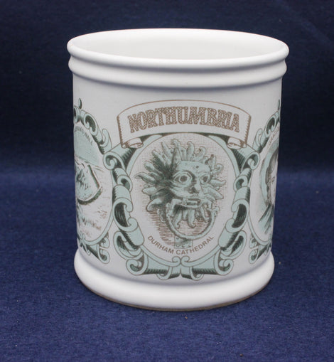 White mug with decorative design and 'Northumbria' text on a blue background