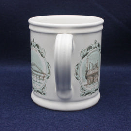 White mug with decorative green designs on a dark blue background