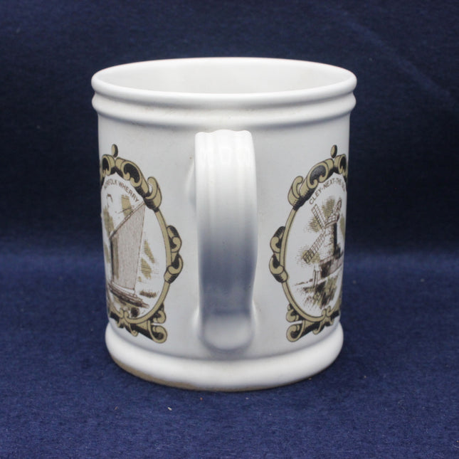 White mug with decorative gold and black designs on a blue background