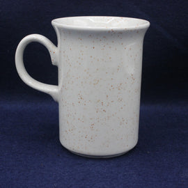 White ceramic mug with speckled pattern on a dark blue background
