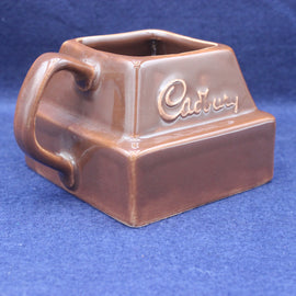 Brown ceramic mug with 'Cadbury' branding on a blue background