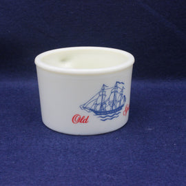 White cup with blue ship design and red text on a dark blue background