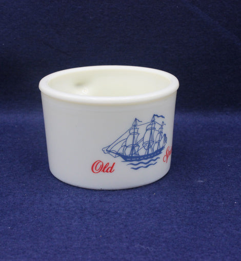 White cup with blue ship design and red text on a dark blue background