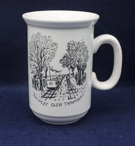 White mug with black illustration of a tram and trees on a blue background