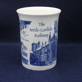 White ceramic mug with blue decorative elements and text on a dark background