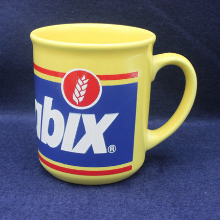 Yellow mug with a blue and red logo on a blue background