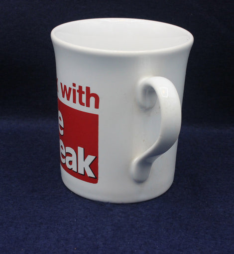 White mug with a red and black label on a dark blue background