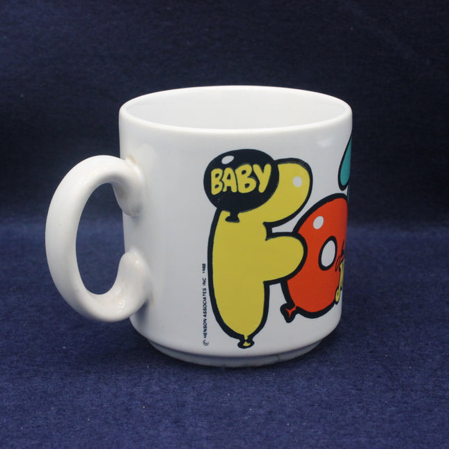White mug with cartoon characters and 'BABY' text on a dark blue background