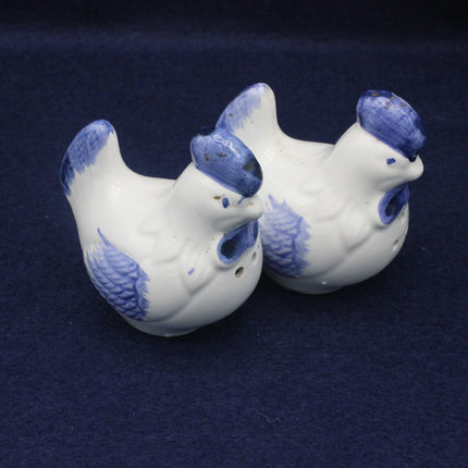 Two ceramic chicken-shaped salt and pepper pots with blue accents on a dark blue background