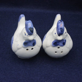 Two ceramic hens with blue accents on a dark blue background