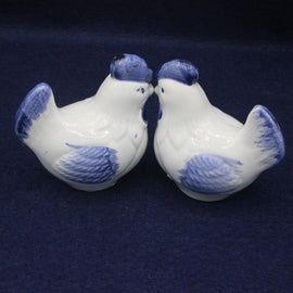 Two ceramic birds with blue accents on a dark background