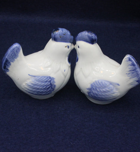Two ceramic birds with blue accents on a dark background