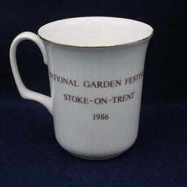 White mug with National Garden Festival text on a dark blue background