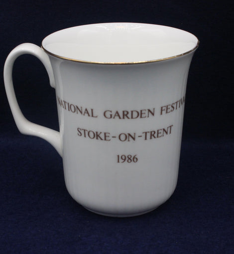 White mug with National Garden Festival text on a dark blue background