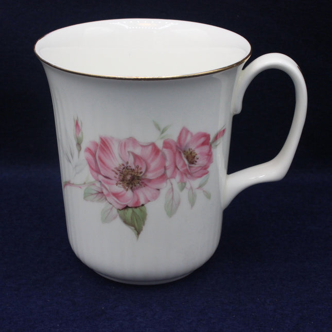 White mug with pink floral design on a dark blue background