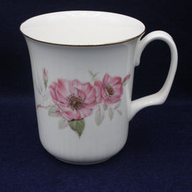 White mug with pink floral design on a dark blue background