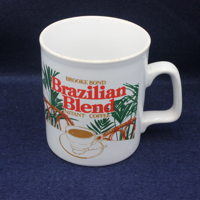 White mug with Brooke Bond Brazilian Blend instant coffee branding on a dark blue background