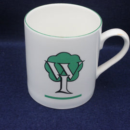 White Women's Institute mug with green and black tree logo on a dark blue background
