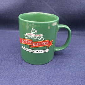 Green mug with 'Betty's Kitchen Coronation Street' branding on a blue background