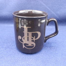 Black mug with gold logo on a blue background
