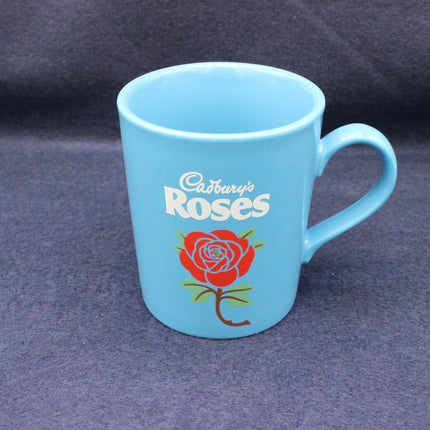 Blue mug with Cadbury's Roses logo on a dark background