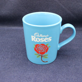 Blue mug with Cadbury's Roses logo on a dark background
