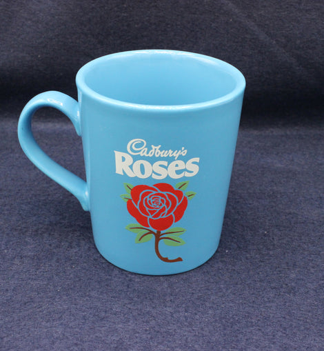 Blue mug with 'Cadbury's Roses' branding on a dark background