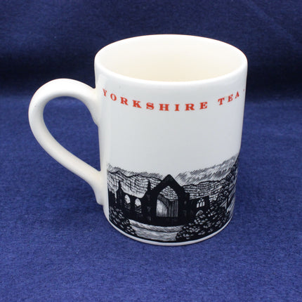 White mug with 'Yorkshire Tea' text and a black and white illustration on a blue background