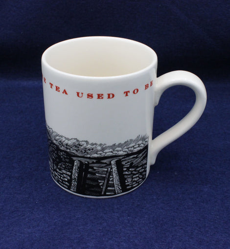 White mug with black and red design on a blue background