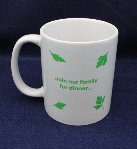 White mug with green text and leaf patterns on a dark blue background