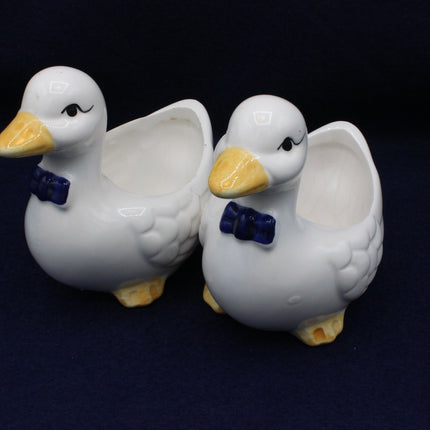 Two ceramic ducks with bow ties on a dark background