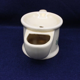 White ceramic tea pot with a small green logo on a dark blue background