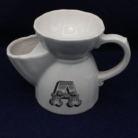 White ceramic tea pot with a handle and decorative letter 'A' on a dark background
