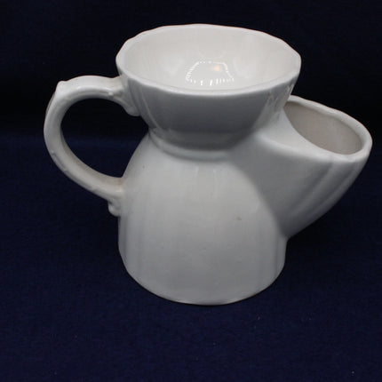 White ceramic pitcher with a spout on a dark background