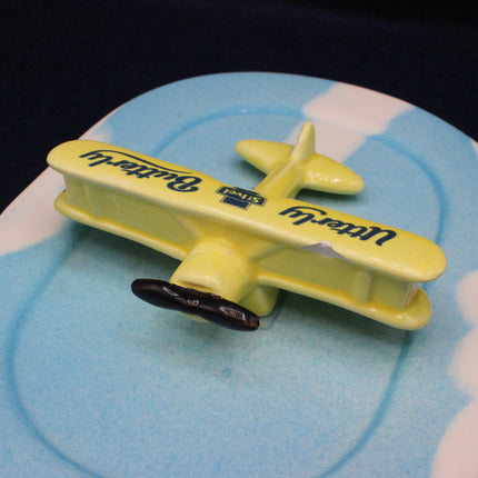 Yellow toy airplane with 'Butterly' branding on a blue and white surface
