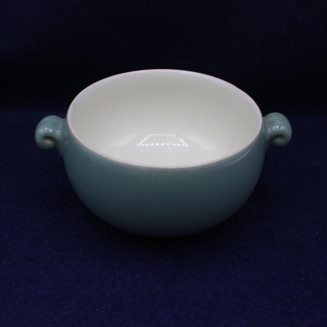 Teal ceramic bowl with handles on a dark blue background