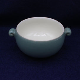 Teal ceramic bowl with handles on a dark blue background