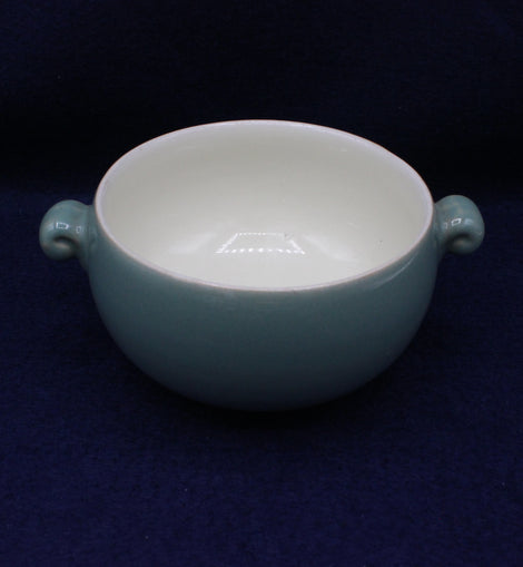 Teal ceramic bowl with handles on a dark blue background