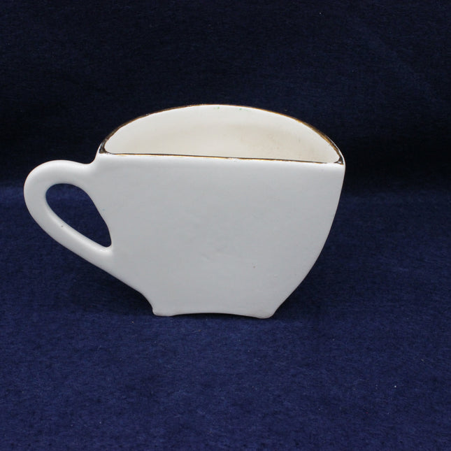 White ceramic teacup-shaped box on a dark blue background