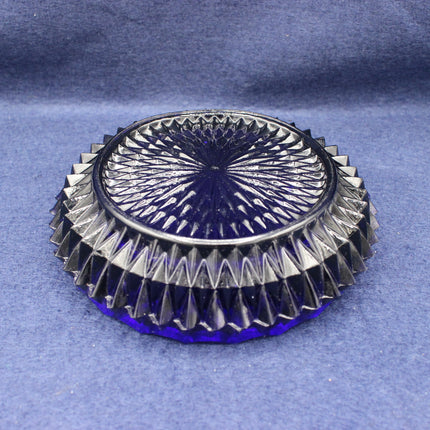 Decorative glass coaster with intricate design on a blue fabric background