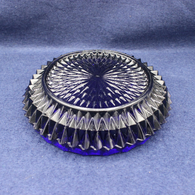 Decorative glass coaster with intricate design on a blue fabric background