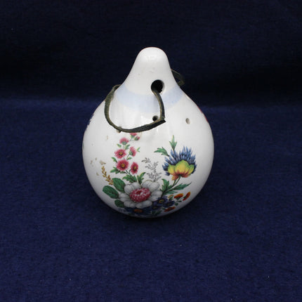 Decorative ceramic ocarina with floral designs on a dark blue background