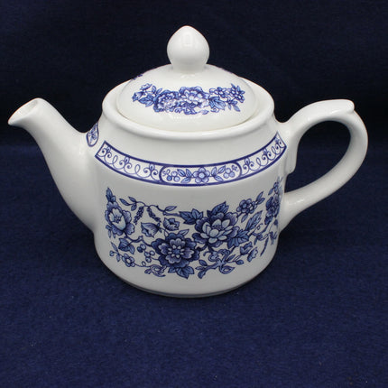 White teapot with blue floral patterns on a dark background