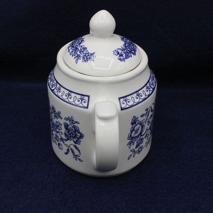 White ceramic teapot with blue floral patterns on a dark background
