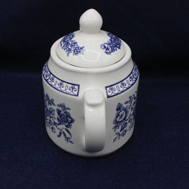 White ceramic teapot with blue floral patterns on a dark background