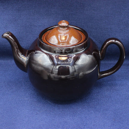 Ceramic teapot with a brown lid on a blue background